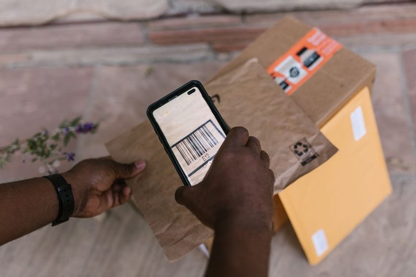 Mesa organizada com anotações de pedidos, códigos de rastreio e um celular mostrando status de entrega